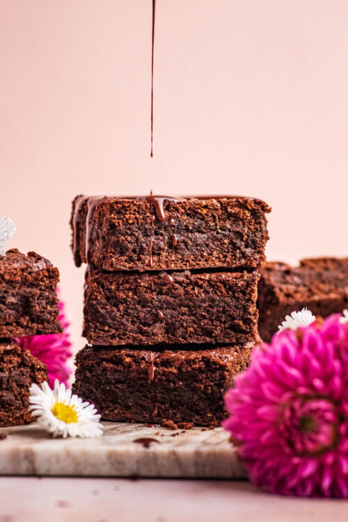 Chocolate drizzling onto a stack of three brownies.
