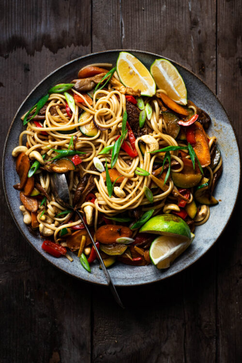 Vegetable soba noodle stir fry in a large bowl with lime wedges.