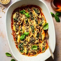 Baked vegan stuffed shells in tomato sauce, in a large baking dish.