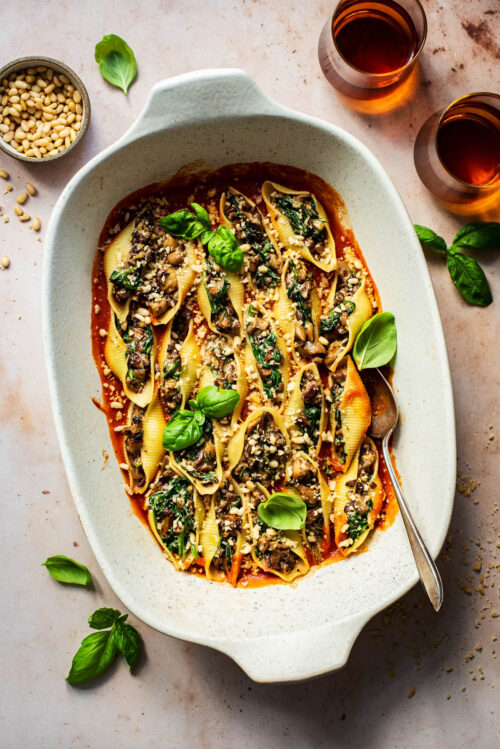 Baked vegan stuffed shells in tomato sauce, in a large baking dish.