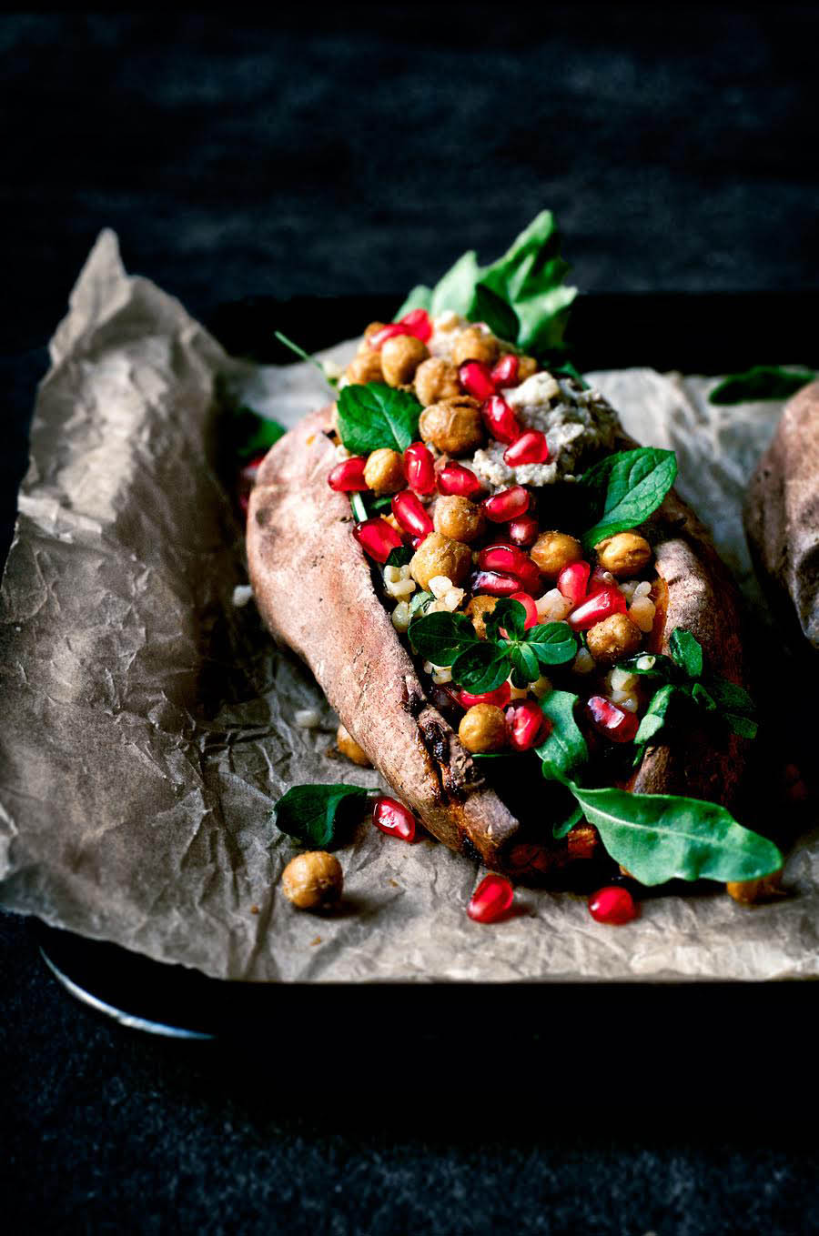 Front view of a stuffed sweet potato with pomegranate.
