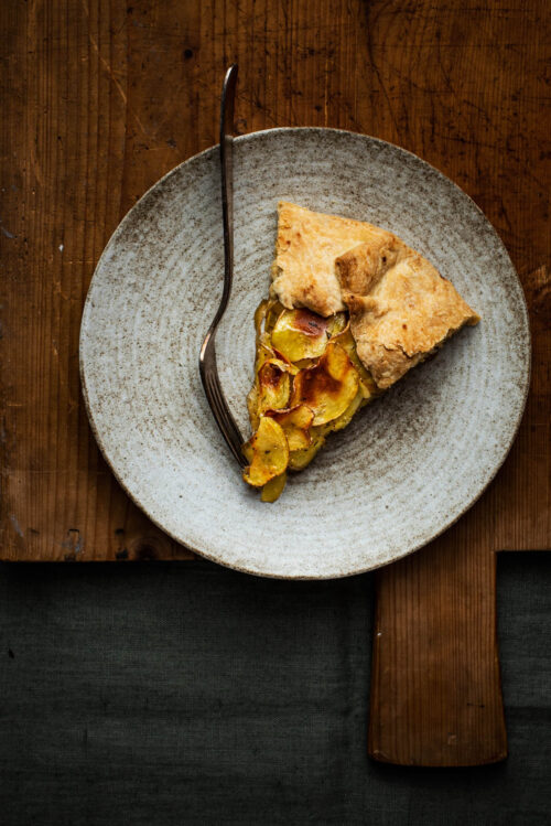 A slice of galette on a plate with a fork.