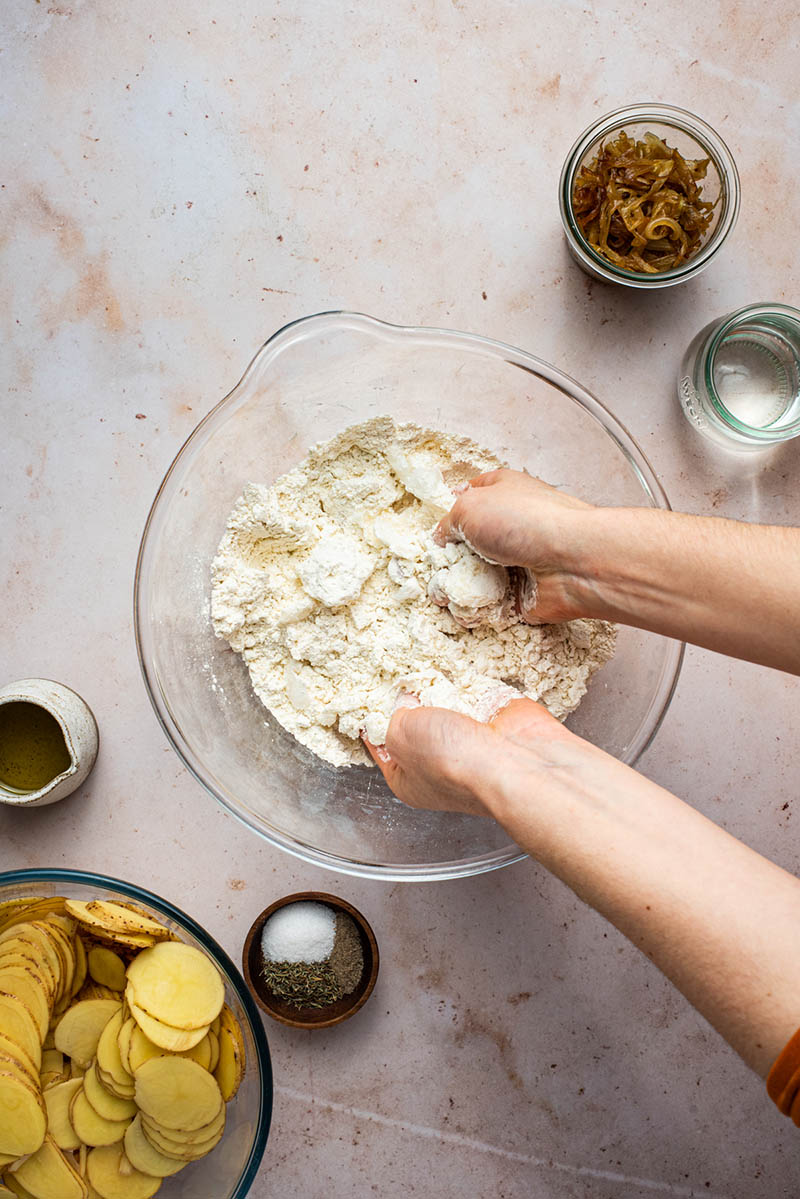 Woman's hands mixing coconut oil into the flour.