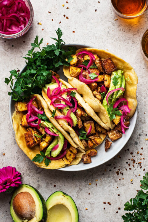 Three potato tacos in a shallow bowl.
