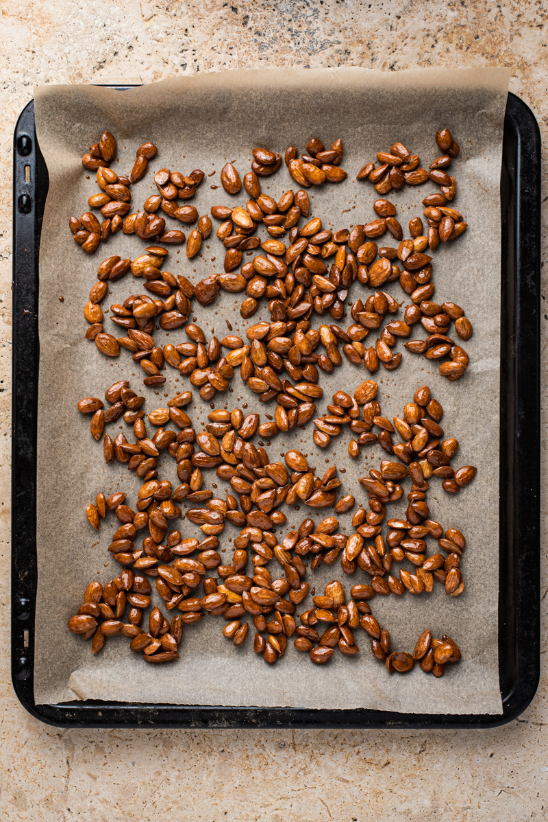 Almonds spread out on the baking sheet.