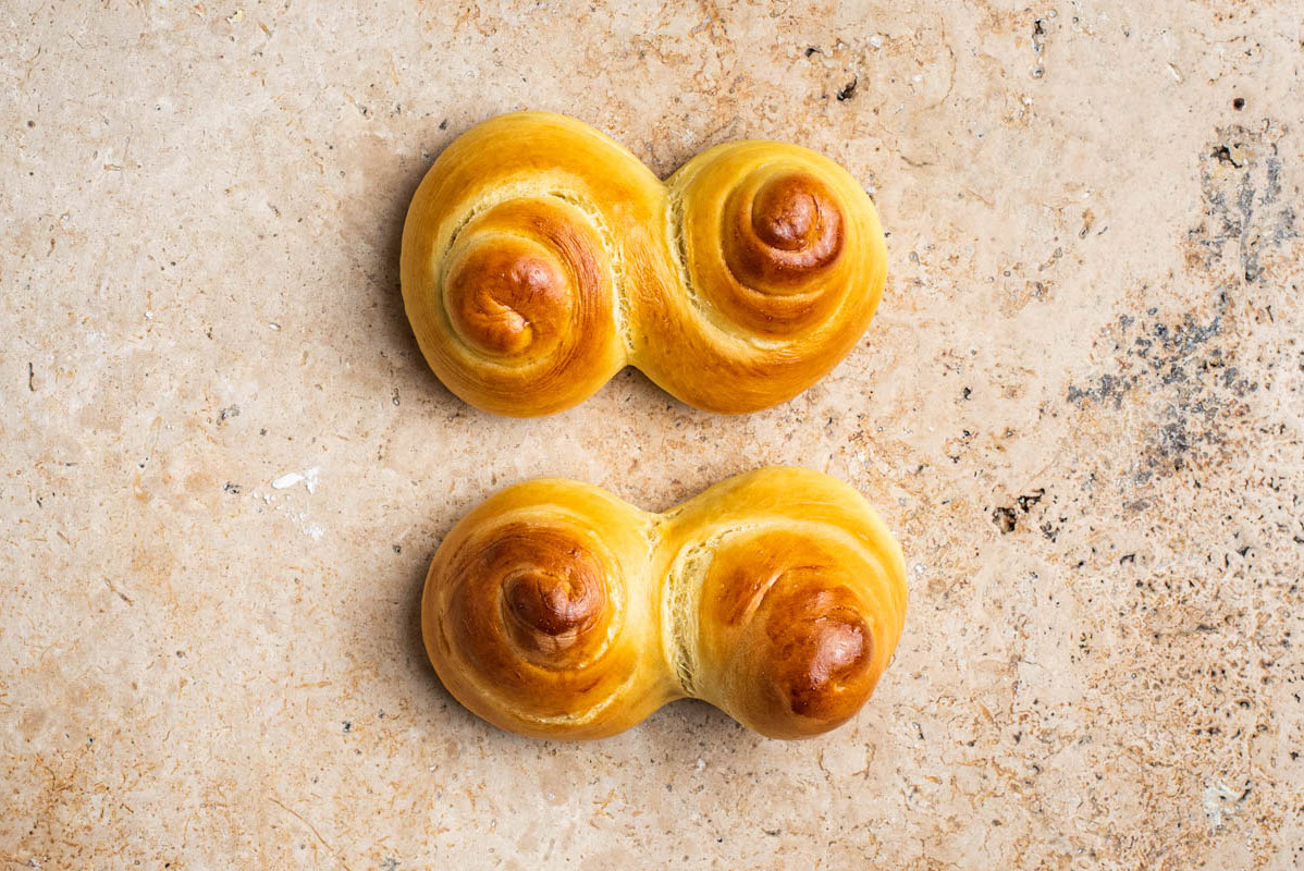 Two buns, top one well proved and bottom over-proved, showing that it's lost the swirl.
