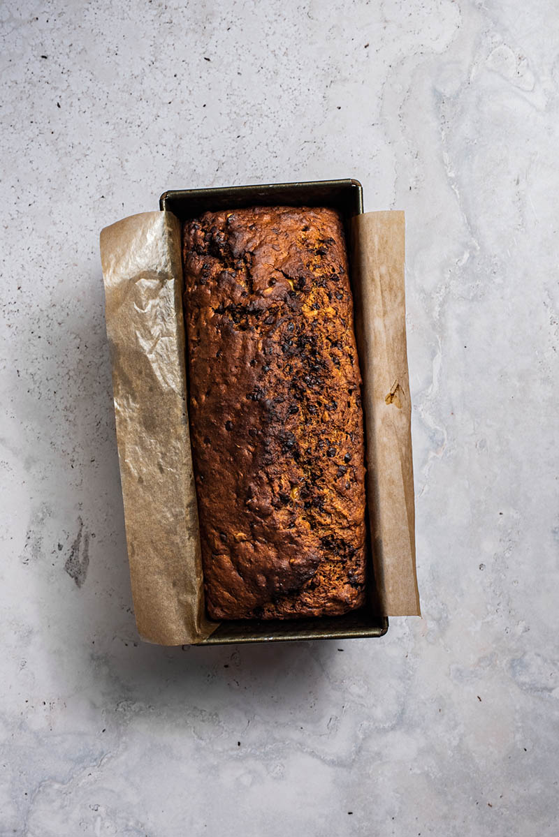 Baked banana bread in a tin with parchment paper.