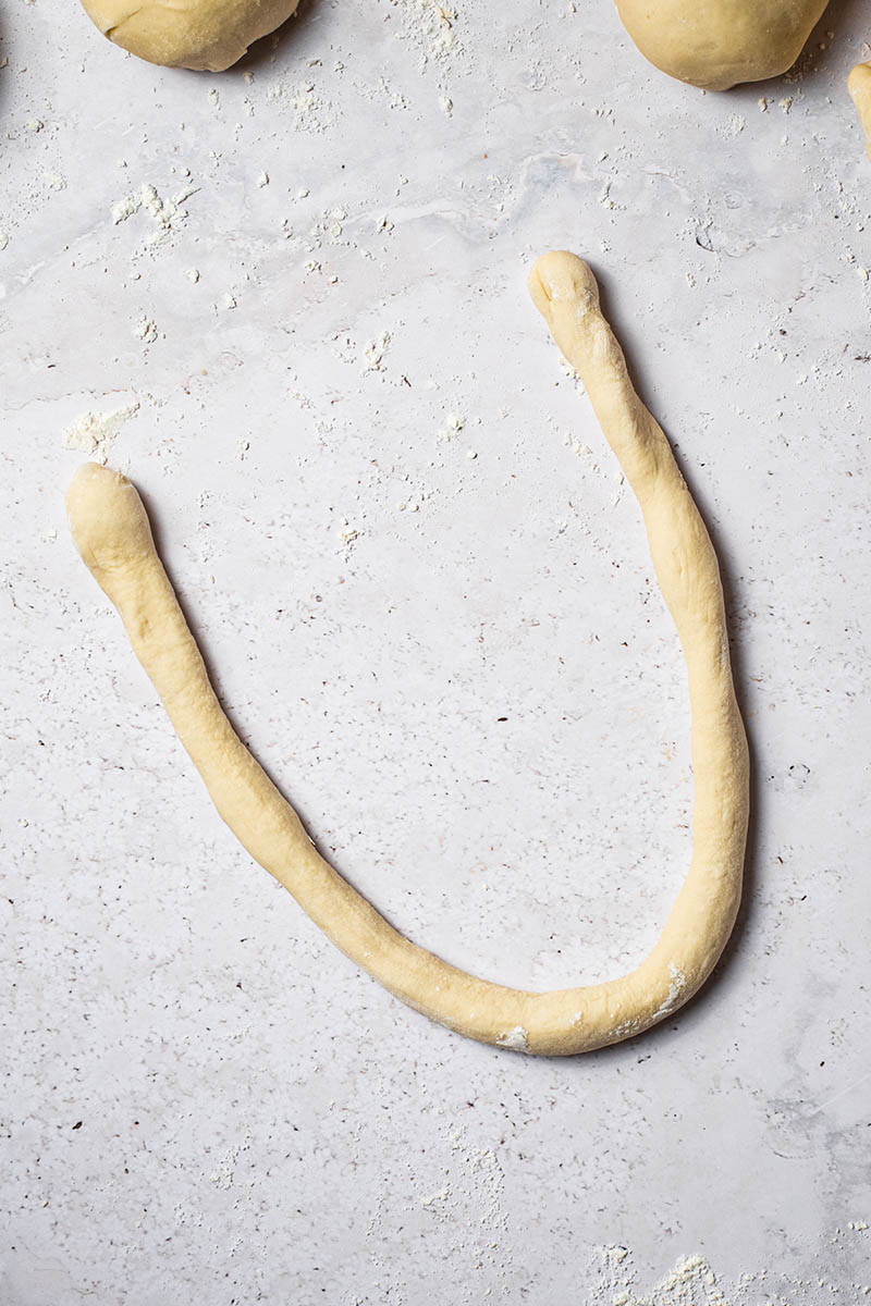 A long strand of pretzel dough in a u-shape.