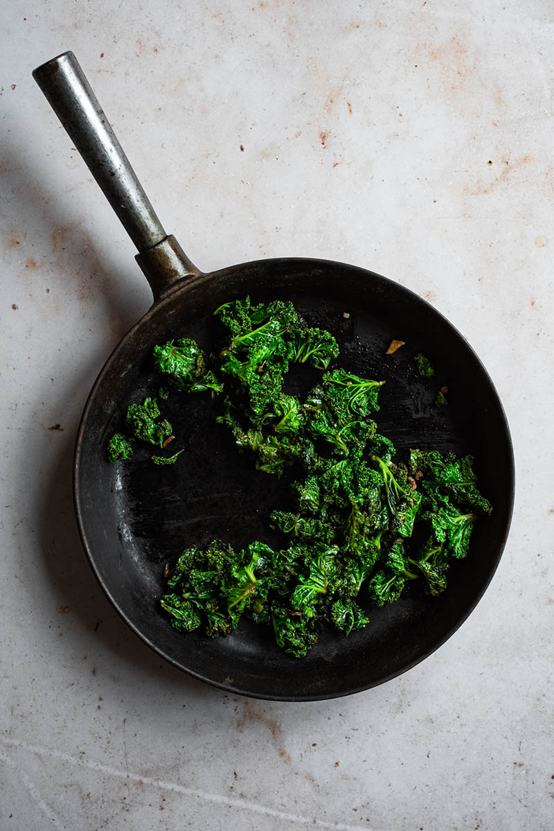 Cooked kale with garlic in a pan.