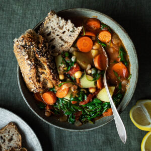 A bowl of chickpea vegetable soup with bread.