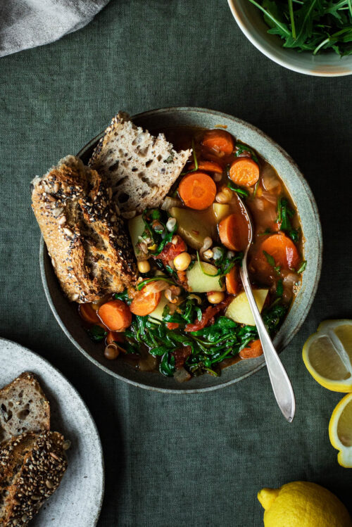 A bowl of chickpea vegetable soup with bread.
