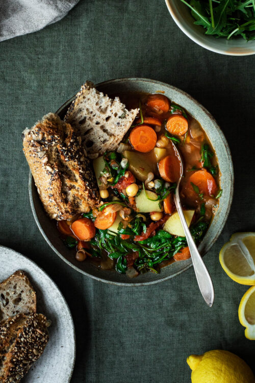 A bowl of chickpea vegetable soup with bread.