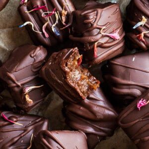 Close up of chocolate covered date caramels, one bitten in half.
