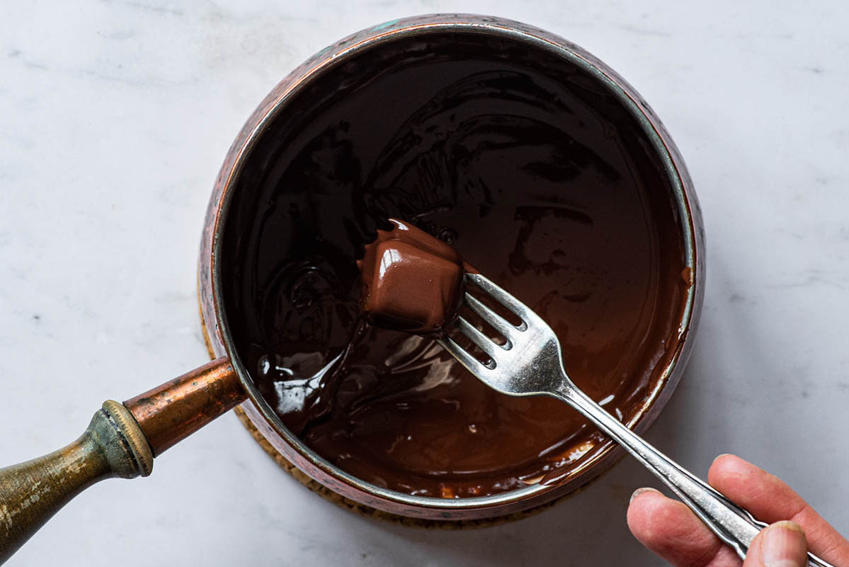 Dipping a caramel in melted chocolate with a fork.