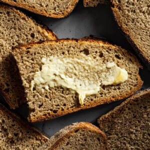 Several halved slices of sourdough bread, one with butter.
