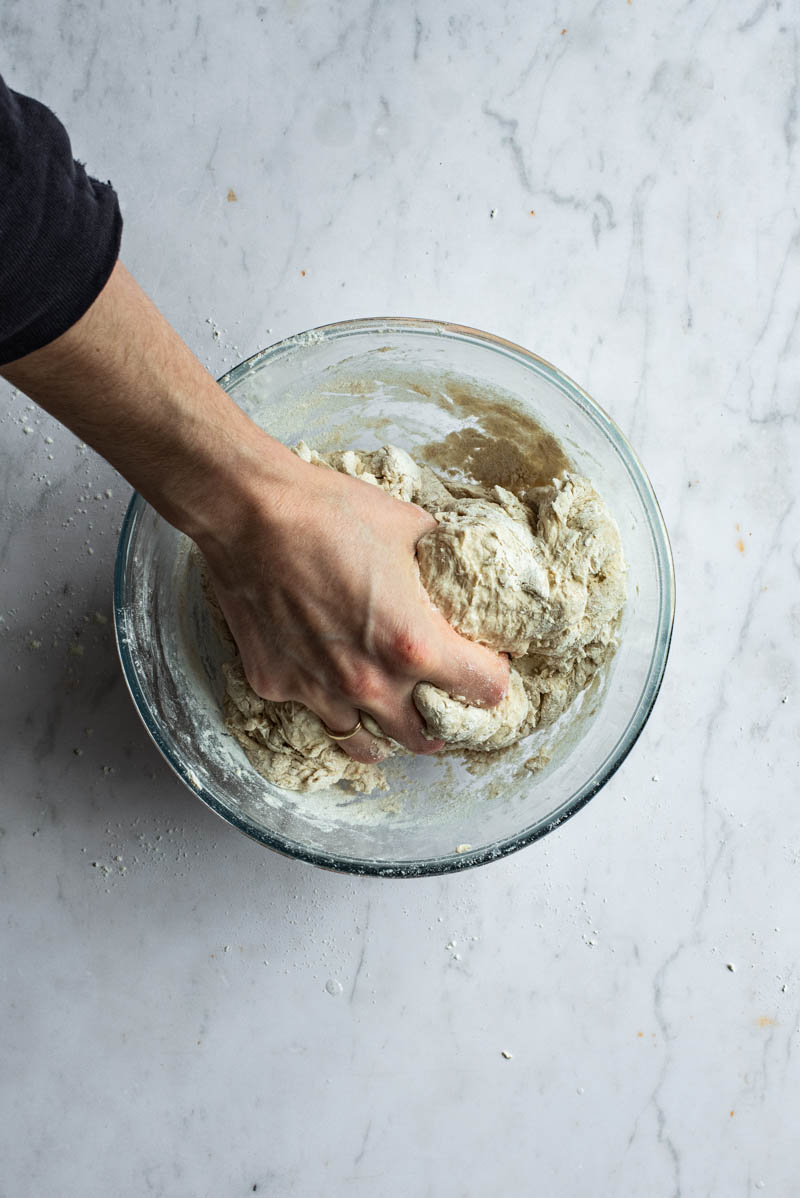 Hand squeezing bread dough to mix.