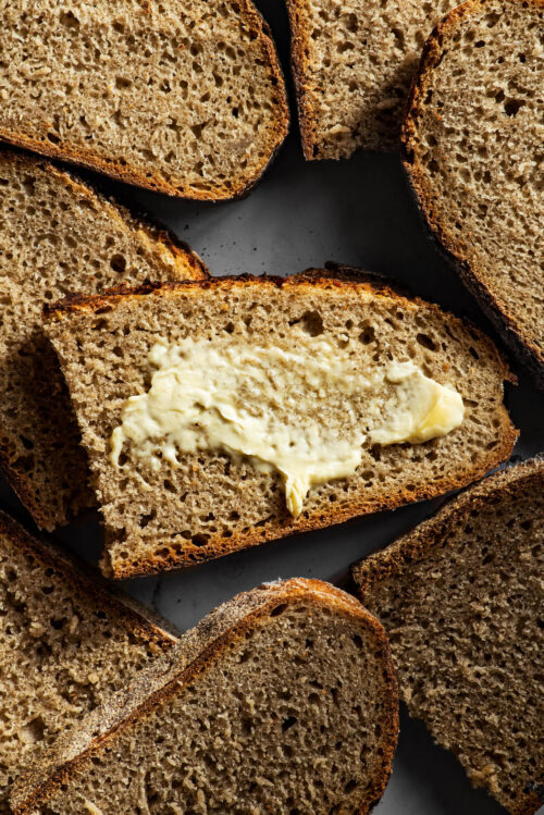 Several halved slices of sourdough bread, one with butter.