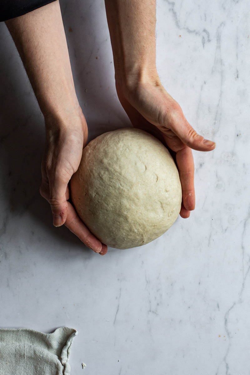 Woman's hands shaping a ball of dough.