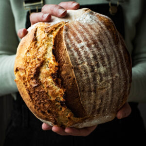 Woman holding a loaf of bread in front of her.