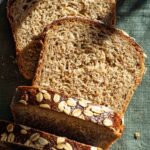 Oat bread with several slices cut, top down view.