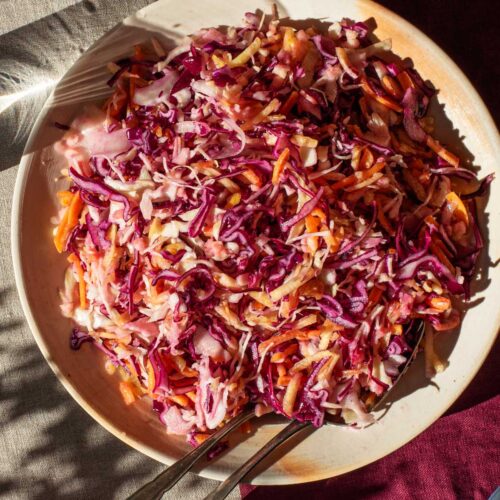 Mixed vegetable coleslaw on a serving plate in hard light.