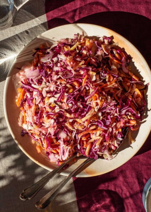 Mixed vegetable coleslaw on a serving plate in hard light.