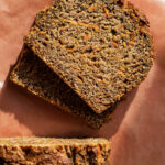 Carrot bread with two slices cut, on parchment paper.