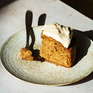 Dramatically lit slice of carrot cake on a plate.