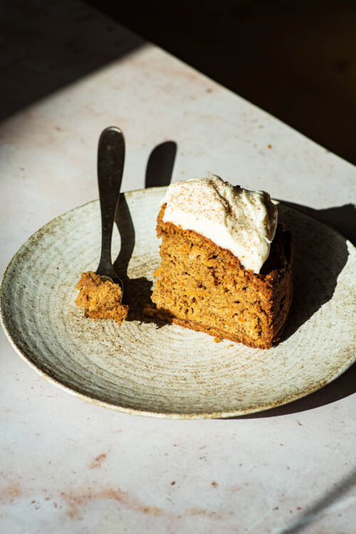 Dramatically lit slice of carrot cake on a plate.
