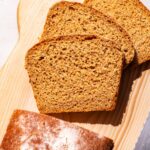 Partly sliced loaf of bread on a cutting board.
