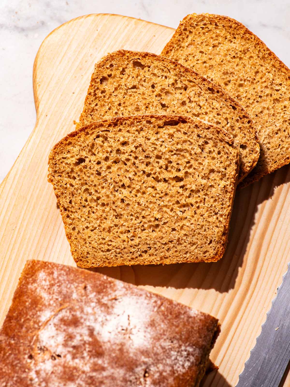 Partly sliced loaf of bread on a cutting board.