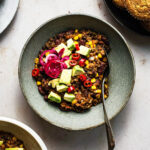 Chili in a shallow bowl with avocado and pickled red onion.