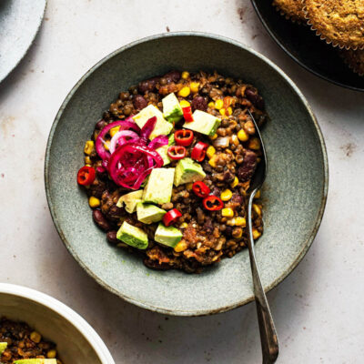 Chili in a shallow bowl with avocado and pickled red onion.