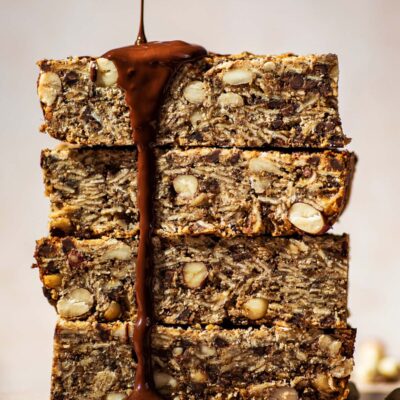 A stack of four granola bars with chocolate being drizzled on them.