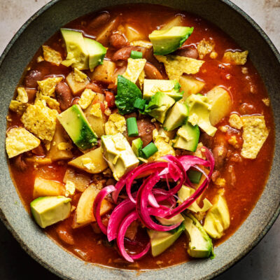 Pinto bean soup with tortilla chips, avocado, and red onion.