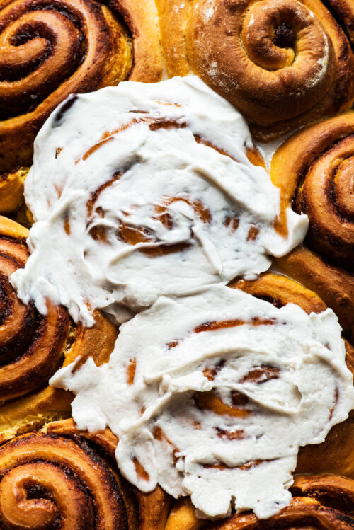 Close up of pumpkin cinnamon rolls with frosting.