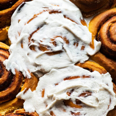 Close up of pumpkin cinnamon rolls with frosting.