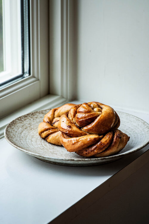 Twisted filled buns on a plate in a windowsill.