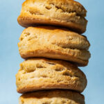 A stack of four vegan coconut oil biscuits with a blue background.