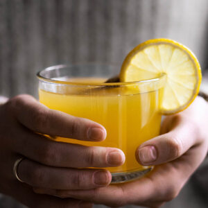 Woman holding a glass of yellow tea.