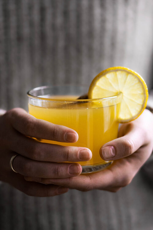 Woman holding a glass of yellow tea.