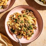 Pasta with mushroom sauce on two plates with salad beside.