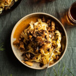 Pasta with mushroom sauce on two plates with drinks.