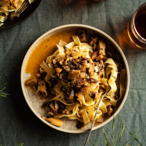 Pasta with mushroom sauce on two plates with drinks.