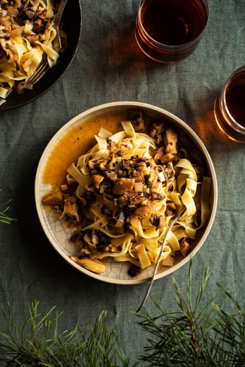 Pasta with mushroom sauce on two plates with drinks.
