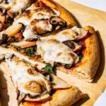 Close up of vegetable pizza on parchment paper.