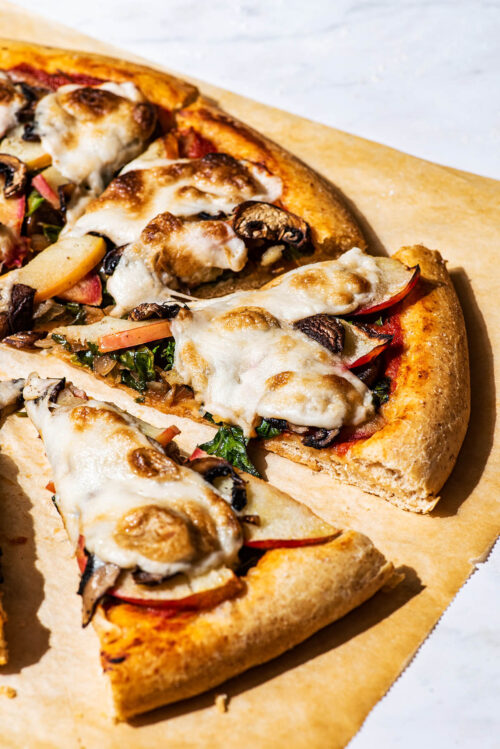 Close up of vegetable pizza on parchment paper.