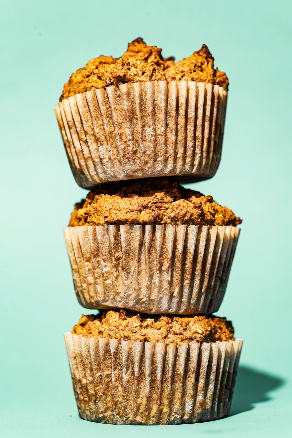 Stack of three muffins against an aqua-green background.
