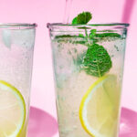 Close up of sparkling water being poured into a glass of mint lemonade.