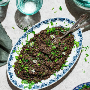 Lentil salad on a platter with chopped herbs and garlic mustard flowers.